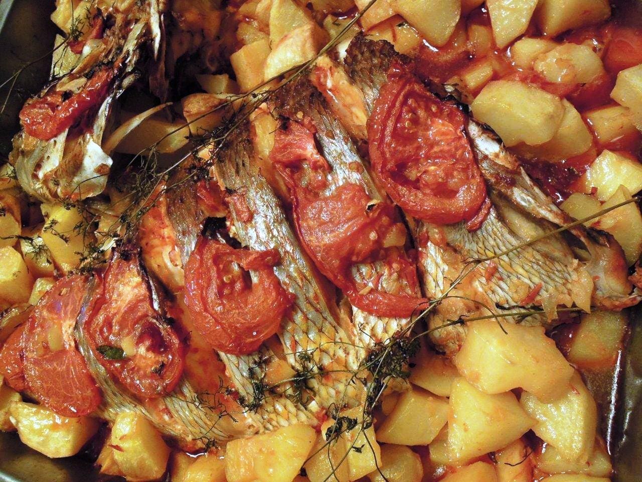 Peixe assado no forno, óptimo para noites frias em que não podemos grelhar o peixe. Com uns golpes do tamanho de postas e o tempero certo é óptimo. Pode comprar o peixe (robalo, sargo, garoupa, cherne, pargo ou o que lhe apetecer) à posta ou inteiro. Se comprar inteiro peça para separar a cabeça e aproveite para fazer uma saborosa sopa de peixe. No peixe inteiro peça à peixeira para dar uns cortes equivalentes uma posta por pessoa Peixe assado no forno Ingredientes para 4 pessoas: 1kg peixe 0,5kg tomate 2 cebolas 1 batata média (ou grande se forem muito batateiros) por pessoa 8 alhos picados 3 folhas de louro 3 cl de sopa de colorau Azeite qb Vinho branco qb Sal Grafe e Faca Peixe assado no forno Antes de mais e 1h a 2h antes salgue o peixe. Entretanto faça o molho para temperar o peixe. Junte os alhos, o louro, o colorau, o azeite, e o vinho branco num recipiente e mexa até ficar homogéneo. Depois de salgado, coloque o peixe num tabuleiro, com rodelas de cebola e tomate por cima que para além de dar gosto, fica muito bonito. Em volta do peixe disponha as batatas cortadas em cubos grandes. Se tiver que utilizar outro tabuleiro para as batatas só tem que as temperar da mesma maneira. Barre tudo com o molho que preparou e leve ao forno aquecido a 180º, tendo o cuidado de ir regando o peixe com o molho para não ficar seco. Está pronto, quando as batatas estiverem macias por dentro e estaladiças por fora. Grafe e Faca Peixe assado no forno Acompanhe com uma boa salada de alface, cebola e coentros. Grafe e Faca Peixe assado no forno