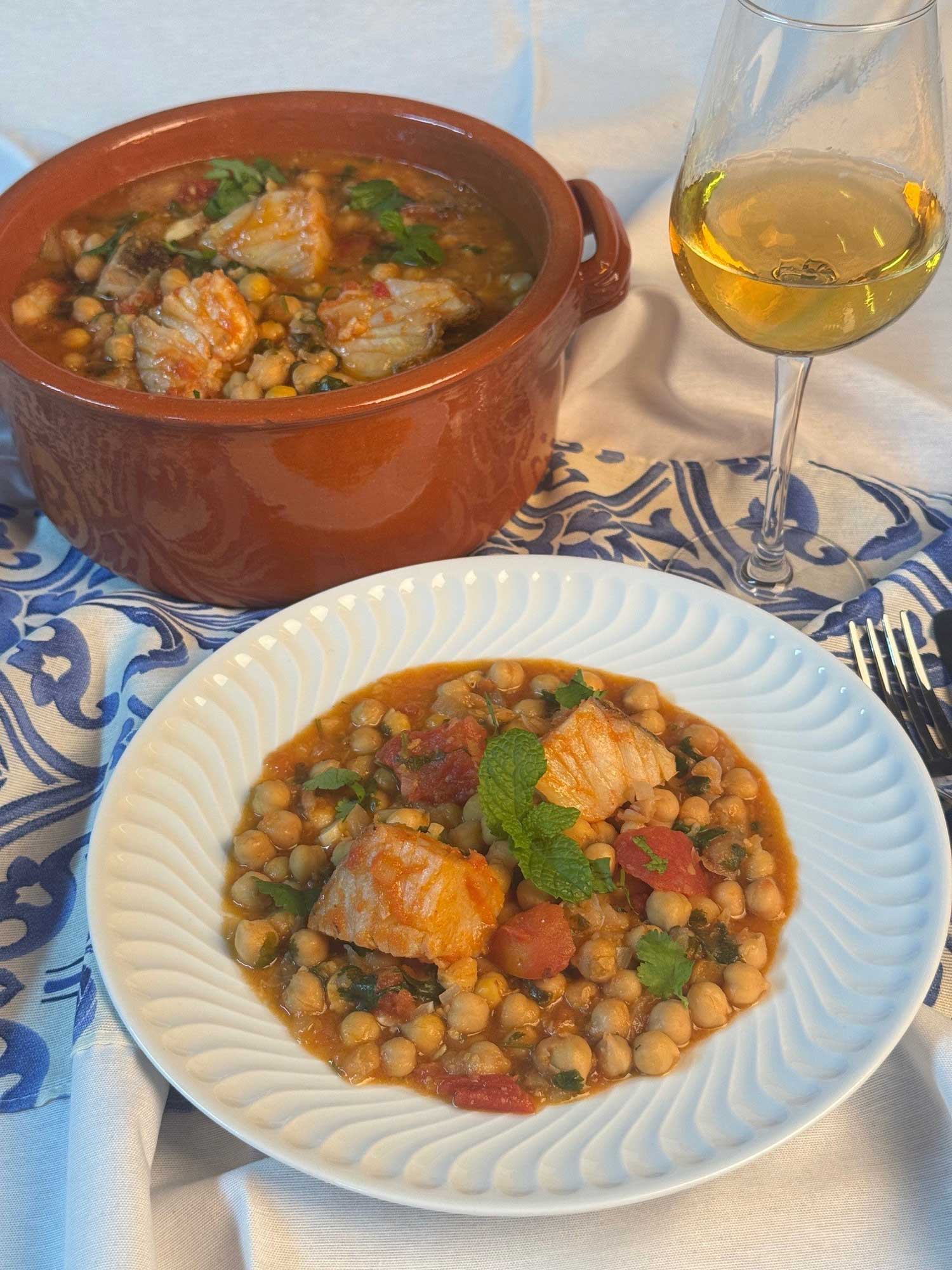 Bacalhau guisado com grão Imagem de Bacalhau guisado com grão num tacho e num prato acompanhado com vinho branco